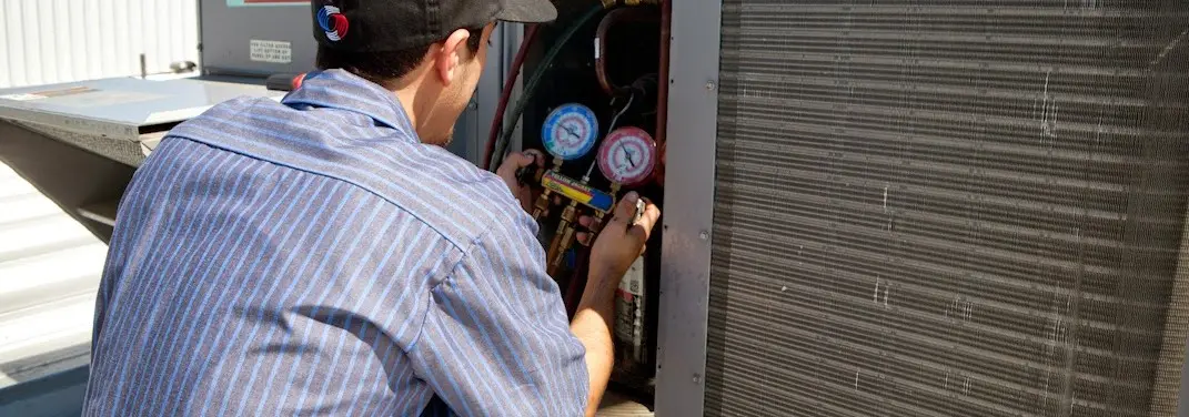 HVAC technician servicing a condenser unit in Pemberton